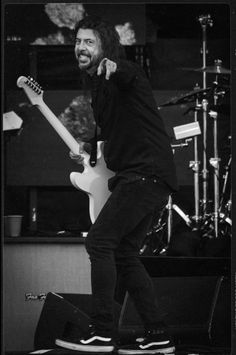 black and white photograph of a man playing an electric guitar in front of microphones