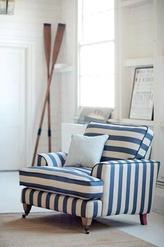 a blue and white striped chair sitting on top of a rug next to a window