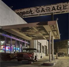 an old car is parked in front of a gas station with a sign that reads sepia garage