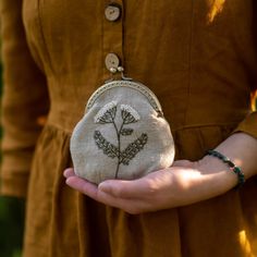 a woman is holding a small purse with a flower embroidered on the front and side