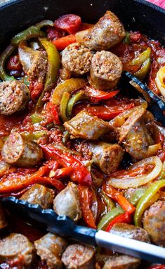 sausage and peppers are being cooked in a skillet with tongs on the side