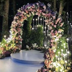 an outdoor ceremony with candles and flowers on the aisle, surrounded by greenery at night