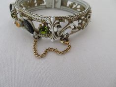 "Fabulous vintage clamper bangle made by Forenza and dating from the 1950's. In antique white enamel it has a lovely flower and leaf design set between herringbone borders which is picked out with gold enamel. The top half of the bangle has round and navette glass gems in shades of green, orange and irridescent purple. The bangle measures approx 0.6\" width at widest point It has a 2.75\" external diameter and 2.25\" internal diameter It simply pulls apart to be fitted on to the wrist and has a Black Agate Ring, Orange Gem, Bangles Making, Glass Gems, Gold Enamel, Design Set, Antique White, White Enamel, Green Orange