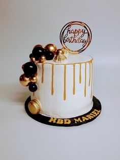 a birthday cake decorated with gold and black balloons