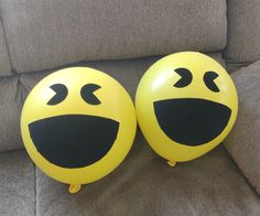 two yellow balloons with faces drawn on them sitting on a couch next to each other