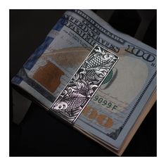 a one dollar bill with a metal cross on it's side, in front of a black background