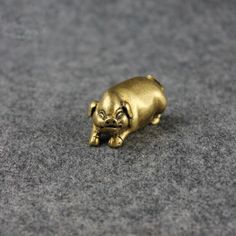 a small gold pig figurine laying on the ground with its mouth open and eyes closed