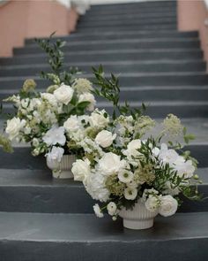 three vases filled with white flowers sitting on top of some steps