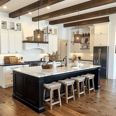 a large kitchen with white cabinets and black island