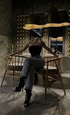 a woman sitting on a chair in front of a table with lights hanging from it