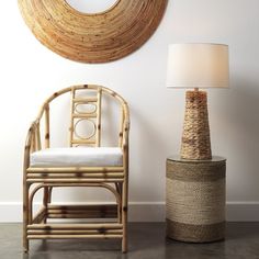 a rattan chair next to a round mirror and lamp in a room with white walls