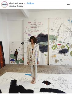 a woman is standing in front of several paintings on the floor with her legs crossed