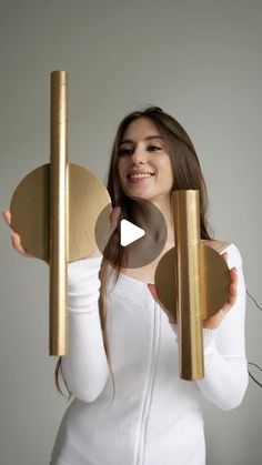 a woman holding two gold objects in her hands