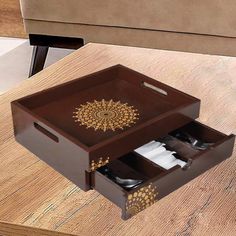 a wooden table topped with a brown tray filled with utensils and napkins