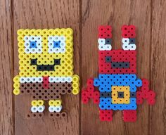 two pieces of perler bead art sitting on top of a wooden table next to each other