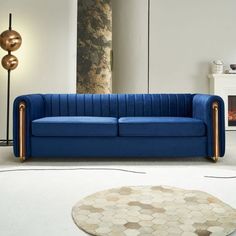 a blue couch sitting in a living room next to a lamp and rug on the floor