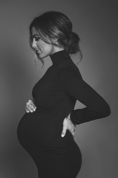 a pregnant woman is posing for a black and white photo with her hands on her hips