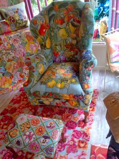 an upholstered chair and footstool on a colorful rug