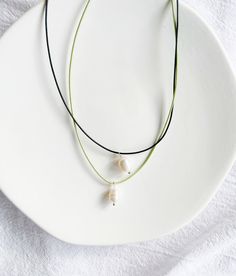 "Freshwater pearls are naturally unique in colour, shape, and texture so your pearl pendant may differ slightly from those pictured.  ∙ A P P R O X ∙ M E A S U R E M E N T S ∙ Each necklace also comes with an additional 2\" extension chain on top of the length you select.   For example, if you select the 14\" necklace option, the total length of the necklace will be 16\" end to end including the clasp and extension chain. ∙ M A T E R I A L S ∙  Strong cotton cord (1mm thickness in black or mint green colour), freshwater pearl, silver plated clasp and extension chain. ∙ C A R E ∙  The colour on silver plated jewellery may fade over time if it is not properly taken care of. To ensure your necklace stays in perfect condition, remove it before coming into contact with water or using any sort o Minimalist Pearl Charm Choker, Minimalist Adjustable Pearl Choker Necklace, Minimalist Choker Necklace With Adjustable Cord, Minimalist Adjustable Cord Choker Necklace, Watercolour Gift, Rainbow Beads, Silver Plated Jewelry, Necklace Choker, Choker Necklaces