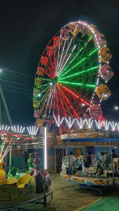 an amusement park at night with ferris wheel and rides