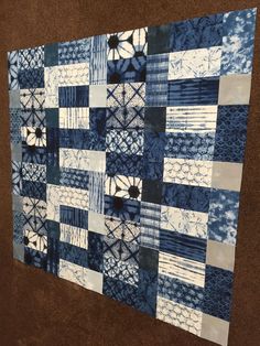 a blue and white quilt hanging on the wall