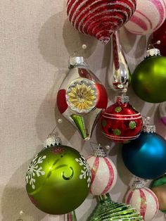 christmas ornaments are hanging on the wall in various colors and designs, including red, green, white and silver