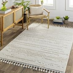 a white rug with tassels on the floor in a living room next to a chair