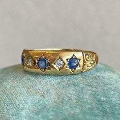 a gold ring with blue and white stones on the inside is sitting on a green surface