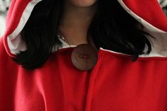 a woman wearing a red and white costume with a button on it's hood