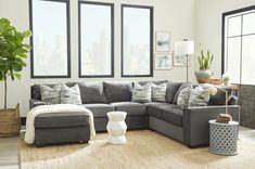 a living room with gray couches and large windows in front of the cityscape