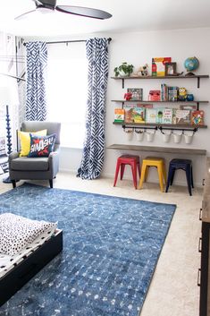 a living room filled with furniture and bookshelves next to a blue rug on top of a hard wood floor