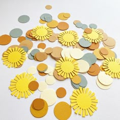 yellow and grey paper flowers on white surface with confetti scattered around the edges