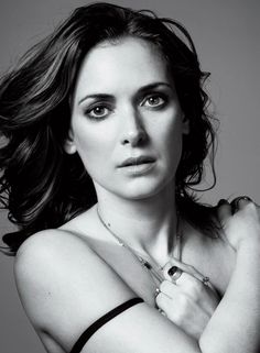 black and white photograph of a woman with her arms crossed looking at the camera while wearing a bra