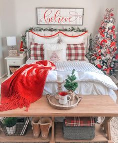 a bedroom decorated for christmas with red and white decorations on the headboard, plaid throw blanket, potted tree, wooden bench