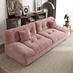 a gray couch sitting on top of a living room floor next to a book shelf