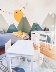 a bedroom with mountains painted on the wall and a table in front of it, next to a bed