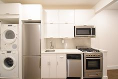 an empty kitchen with white cabinets and appliances in it's center island, next to a washer and dryer