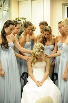 a group of bridesmaids standing around a woman in a white dress with her hair pulled back