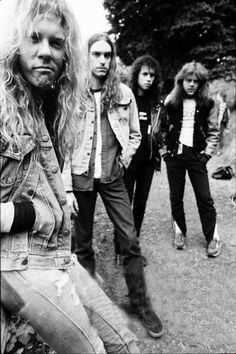 an old black and white photo of four people standing in front of some trees with their faces close to the camera