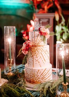 a white and gold wedding cake sitting on top of a table next to some candles