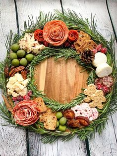 a wreath made out of different types of food on a wooden table with pine cones and berries