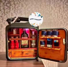 an open suitcase sitting on top of a wooden table filled with bottles and liquors