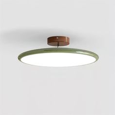 an overhead view of a circular light fixture on a white wall with a brown leather belt hanging from the ceiling