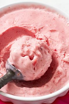 a bowl filled with ice cream on top of a pink table cloth next to a spoon