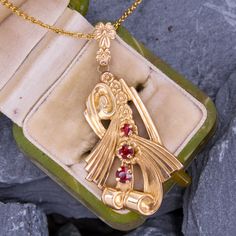 This scrolling circa 1940s slide pendant is crafted in 10k yellow gold and is features three prong set round garnets.  The bail features a floral motif and is stamped "ESEMCO."  The pendant hangs on a modern 14k yellow gold cable chain. Art Deco Jewelry With Vintage Charm For Anniversary, Art Deco Vintage Charm Jewelry For Anniversary, Vintage Ruby Pendant Jewelry, Art Deco Ruby Jewelry Hallmarked, Yellow Gold Art Deco Jewelry For Vintage Events, Art Deco Yellow Gold Jewelry For Vintage Events, Art Deco Pendant Jewelry With Polished Finish, Art Deco Polished Pendant Jewelry, Art Deco Pendant With Polished Finish