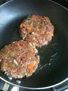 two hamburger patties cooking in a frying pan