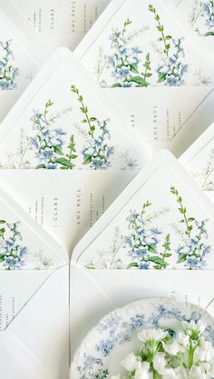 six envelopes with blue and white flowers on them are arranged next to a plate