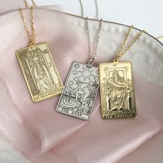 three different pendants on a plate with pink fabric in the background and one gold, one silver