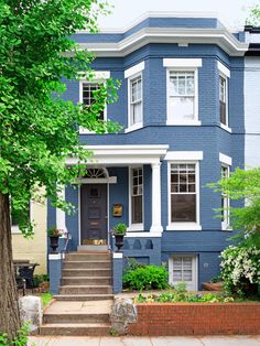 a blue house with steps leading up to the front door and trees on either side