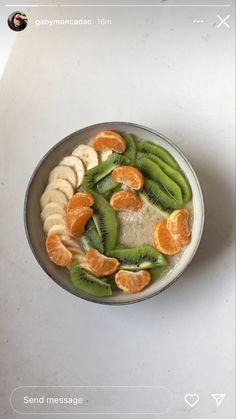 a bowl filled with sliced fruit on top of a white counter next to a cell phone